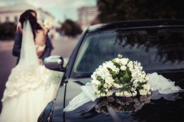 Recém-casados abraçando perto do carro
 - Foto, Imagem