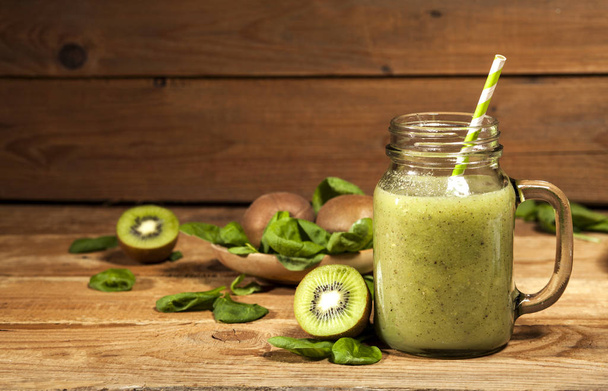Freshly blended green smoothie in glass jar with straw. Wooden background. - Zdjęcie, obraz