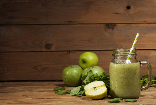 Freshly blended green smoothie in glass jar with straw. Wooden background. - Foto, imagen
