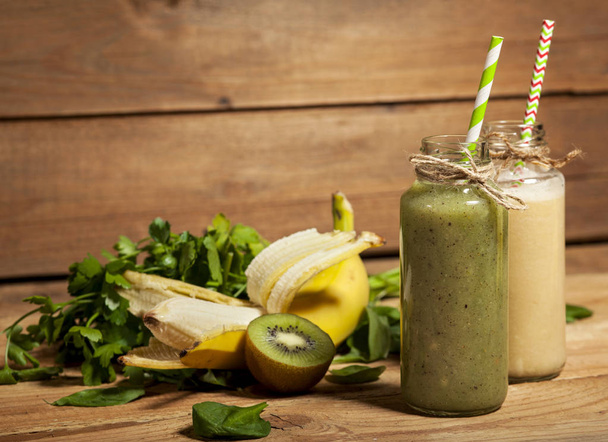Freshly blended green and banana smoothies in glass bottles with straws. - Zdjęcie, obraz