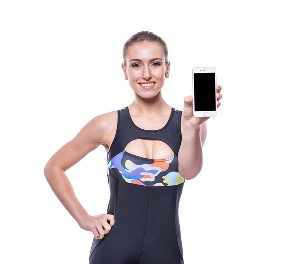 Happy fitness young woman wearing sportswear tracksuit showing blank smartphone screen isolated on white background. - Foto, immagini