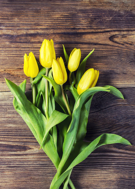 Букет желтых тюльпанов на деревянном столе
 - Фото, изображение