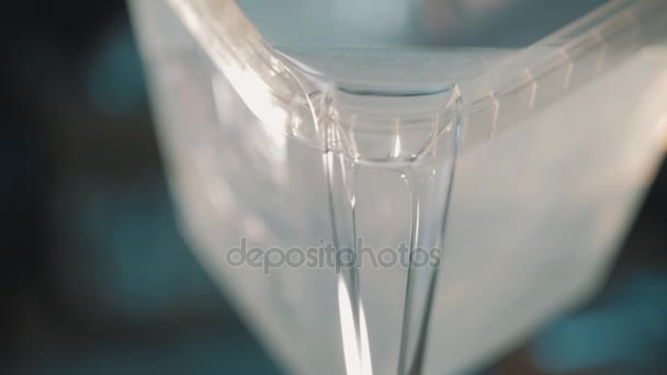 klare Flüssigkeit strömt langsam aus quadratischem transparentem Kunststoffbehälter - Filmmaterial, Video