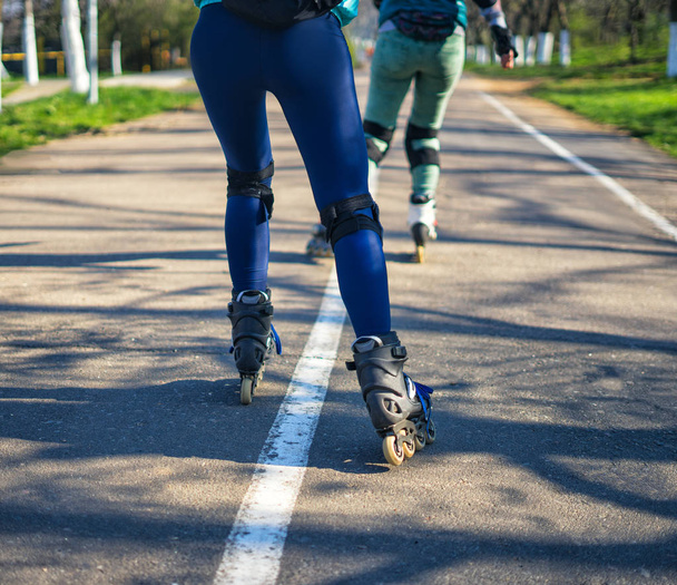 ローラー スケートの 2 人の女の子が互いの横の道に沿って乗る - 写真・画像