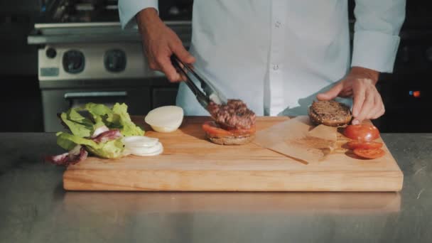 Jefe de cocina masculina en bata blanca haciendo hamburguesa, pone carne a la parrilla
 - Metraje, vídeo