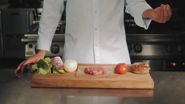 Chefe de cozinha masculino em roupão branco goteja sal grosso em carne não cozida
 - Filmagem, Vídeo