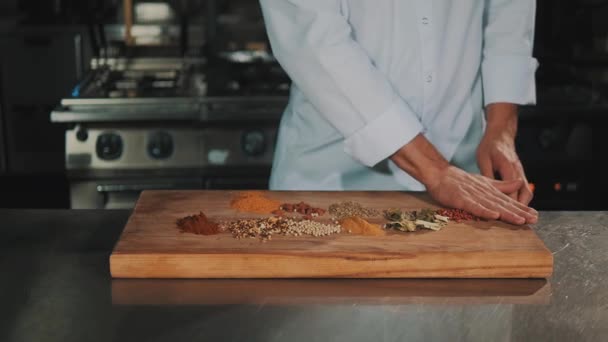 Mužské vaření náčelník v bílém rouchu vyvolá koření z dřevěné prkénko - Záběry, video