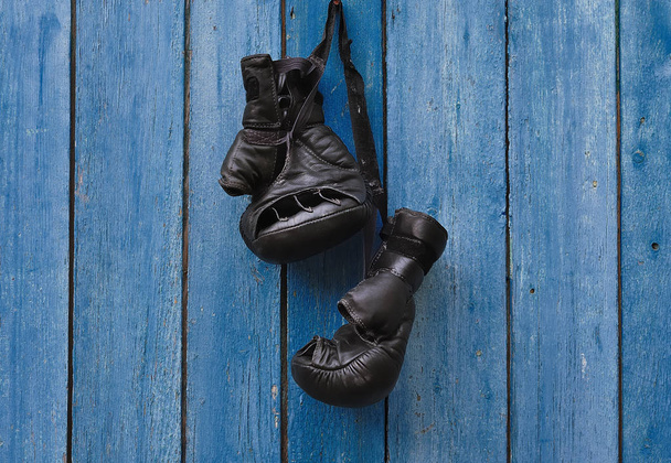 Black vintage boxing gloves hanging on an old rusty nail  - Φωτογραφία, εικόνα