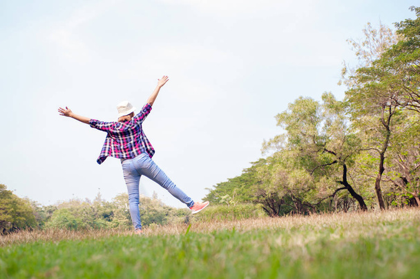 woman jumping enjoying relax on green grass and flower field in park - Foto, Imagem