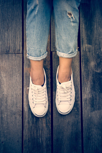 White shoes,Fashion woman's legs with sneakers seated on Wooden floor - Foto, immagini