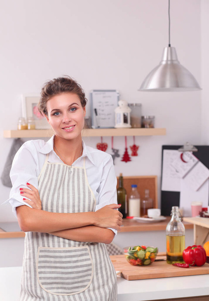 Smiling young woman standing in the kitchen - Photo, image