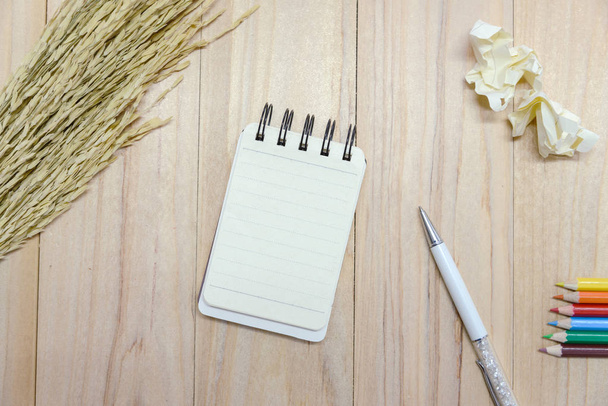 Small note book paper (notepad) for writing information with pen, color pencil and crumpled paper balls on wooden table. view from above - Photo, Image