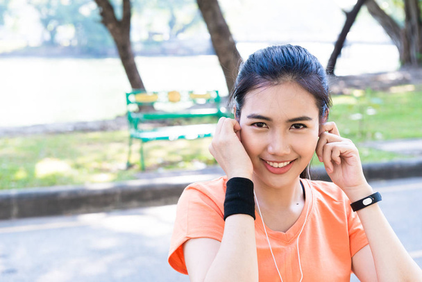 Young beautiful attracttive Asian female runner listening to mus - Photo, Image