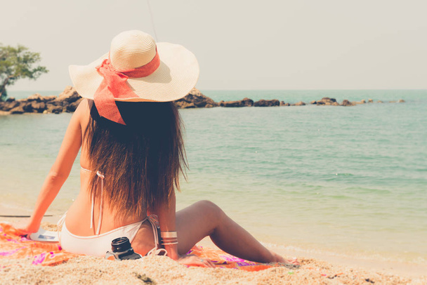 Beautiful asian bikini woman sitting on beach looking into sea - Fotografie, Obrázek