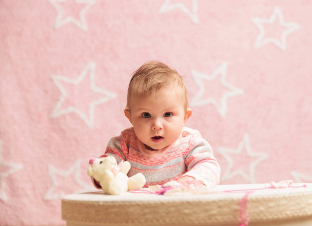 baby girl standing near toy box with little bear on - Fotó, kép