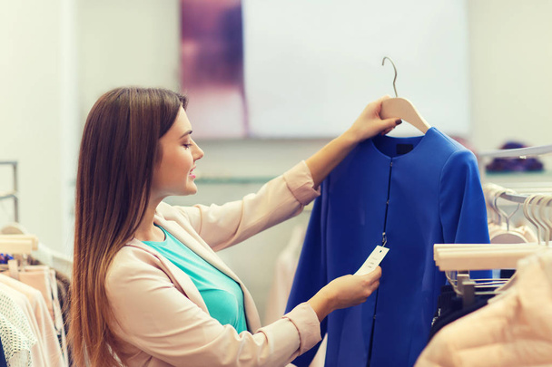 happy young woman choosing clothes in mall - Фото, зображення