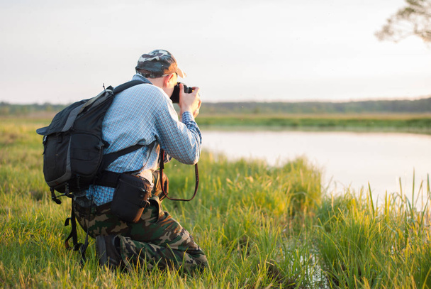 Мужской фотограф смотрит на озеро на закате
, - Фото, изображение