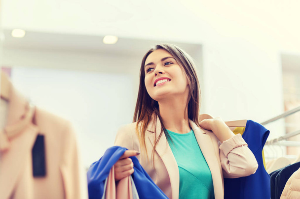 happy young woman choosing clothes in mall - Fotó, kép