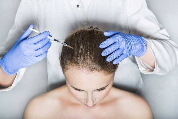 Doctor aesthetician makes head beauty injections to female patient on white background - 写真・画像