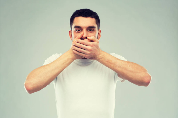 man in white t-shirt covering his mouth with hands - Fotó, kép