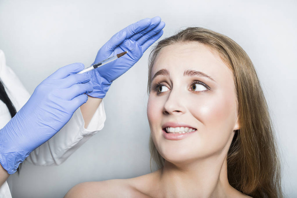 Doctor aesthetician trying to make head beauty injections to female patient - Foto, afbeelding