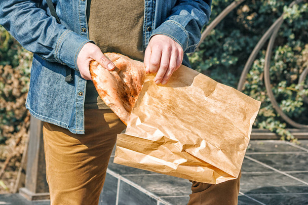 пожилой человек кладет хлеб в бумажный пакет
 - Фото, изображение