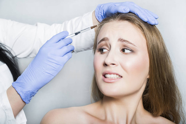 Doctor aesthetician trying to make head beauty injections to female patient - Photo, image