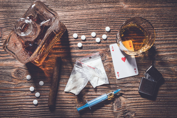 Addiction concept. Hard drugs and alcohol on wooden table - 写真・画像