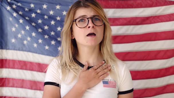Szőke fiatal nő énekel, Amerikai zászló előtt - Felvétel, videó