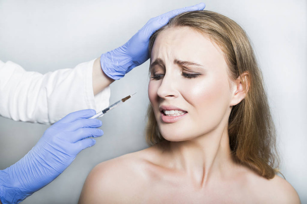 Doctor aesthetician trying to make head beauty injections to female patient - 写真・画像