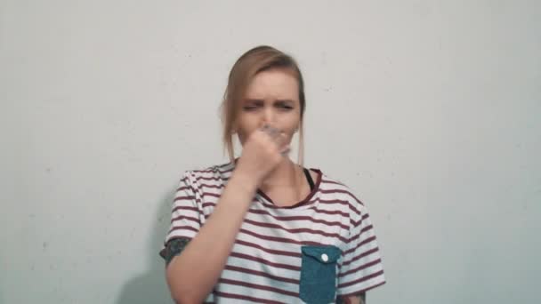 Pretty blonde girl in striped shirt, smells something awful and cover up nose - Footage, Video