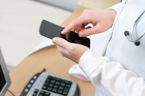 A female doctor texting on smartphone - Фото, зображення