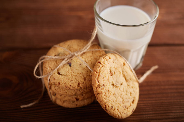 Cookies en melk. Chocoladeschilferkoekjes en een glas melk. Vintage look. Lekkere koekjes en glas melk op rustieke houten achtergrond. Voedsel, junkfood, koken, bakken en eten concept - Foto, afbeelding