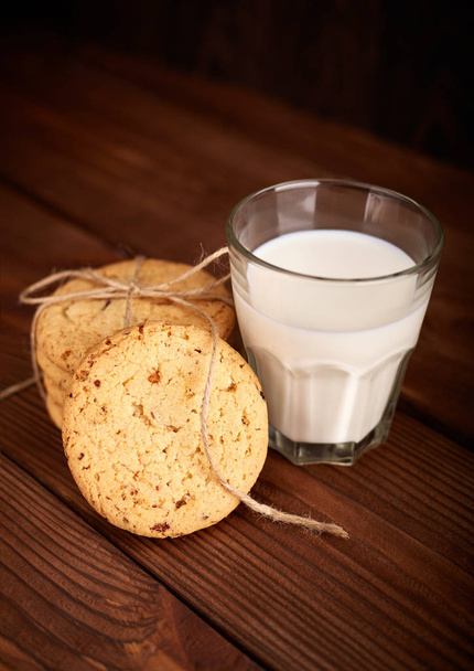Cookies and milk. Chocolate chip cookies and a glass of milk. Vintage look. Tasty cookies and glass of milk on rustic wooden background. Food, junk-food, culinary, baking and eating concept - Фото, изображение