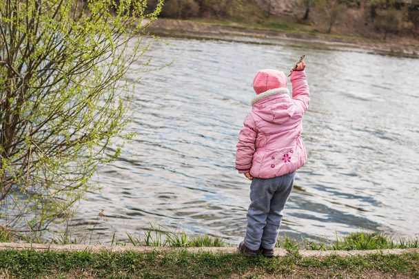 Child throws a stick into the water - Foto, Imagen