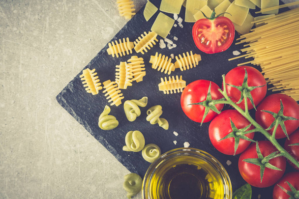 Ингредиенты пасты. Черри помидоры, макароны, свежий базилик, специи на каменном фоне
 - Фото, изображение