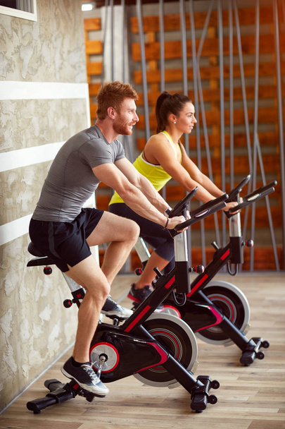 Couple trains on bike in gym - Foto, afbeelding