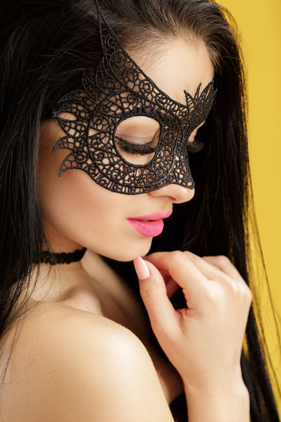 portrait of beautiful sensual woman in black lace mask on yellow background. sexy girl in venetian mask - Photo, Image