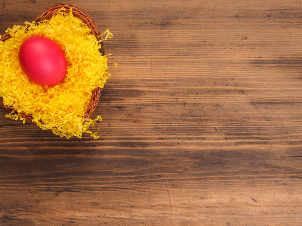 Huevo de gallina de color sobre fondo de paja de color amarillo brillante y mesa de madera vieja. La vista desde arriba
. - Foto, Imagen