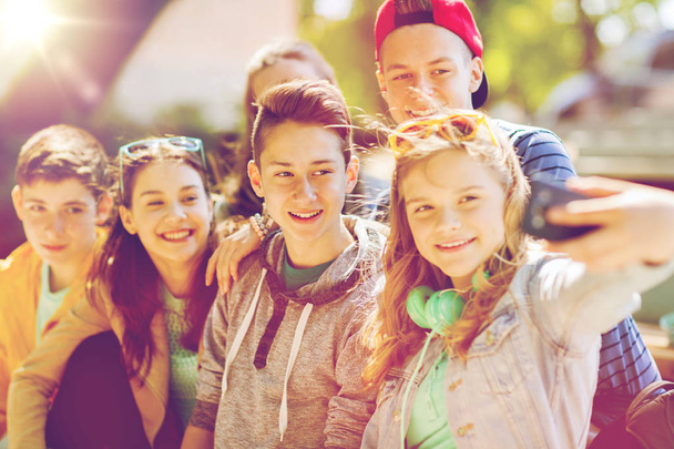 szczęśliwy nastoletnich uczniów biorąc selfie przez smartfona - Zdjęcie, obraz