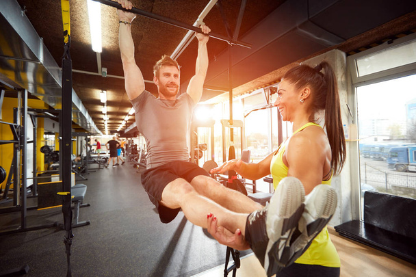 Man with trainer in gym on exercise equipment - Photo, image
