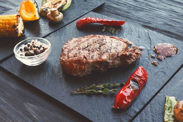Gegrild rundvlees biefstuk close-up op donkere houten tafel achtergrond - Foto, afbeelding