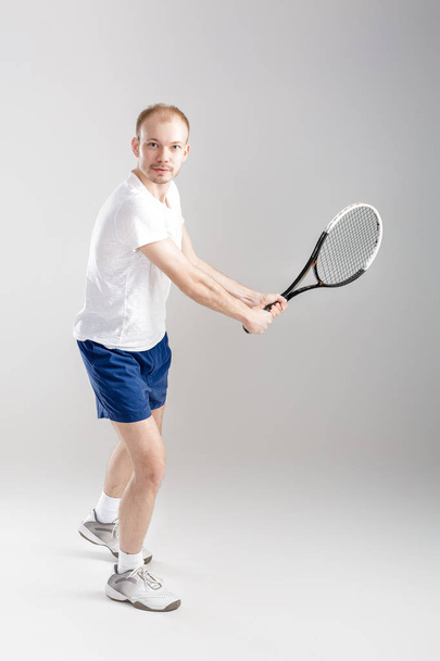 young tennis player plays tennis on grey background - Photo, Image