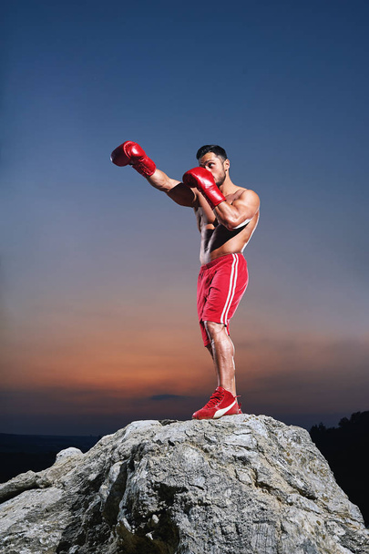 Muscular male boxer training outdoors - Photo, image