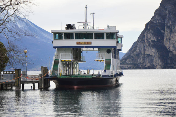 View of Lake Garda with moor ferry and mountain landscape winter time, Riva del Garda, Italy - 写真・画像