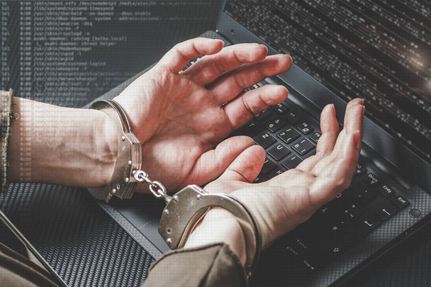ノート パソコンのキーボードやデジタル コード周りで手錠で後ろ手にハッカーが逮捕。サイバー犯罪の概念。マット調. - 写真・画像