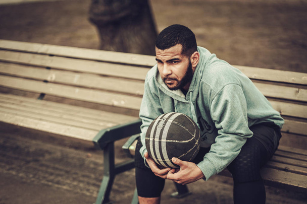 Jugador afroamericano de streetball descansando al aire libre
 - Foto, Imagen