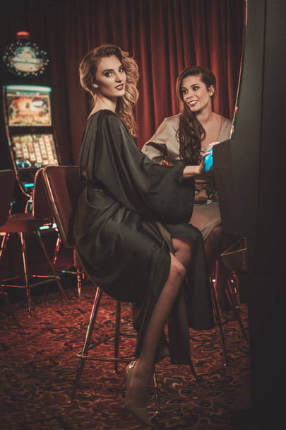 schöne Frauen in der Nähe von Spielautomaten in einem luxuriösen Casino-Interieur - Foto, Bild