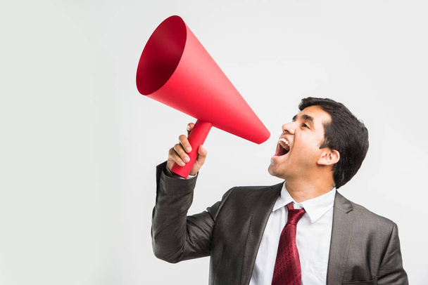 homme d'affaires indien annonçant ou diffusant des nouvelles en utilisant haut-parleur rouge ou méga micro composé de papier, isolé sur fond blanc
 - Photo, image