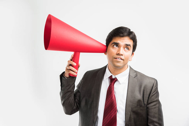 homme d'affaires indien écouter une annonce ou des commérages à travers haut-parleur rouge ou méga micro composé de papier, isolé sur fond blanc
 - Photo, image